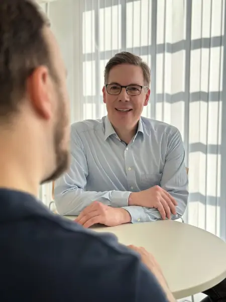 Symbolbild Vertriebsbücher: Ein junger Mann am Computer zwischen zahlreichen Unterlagen.
