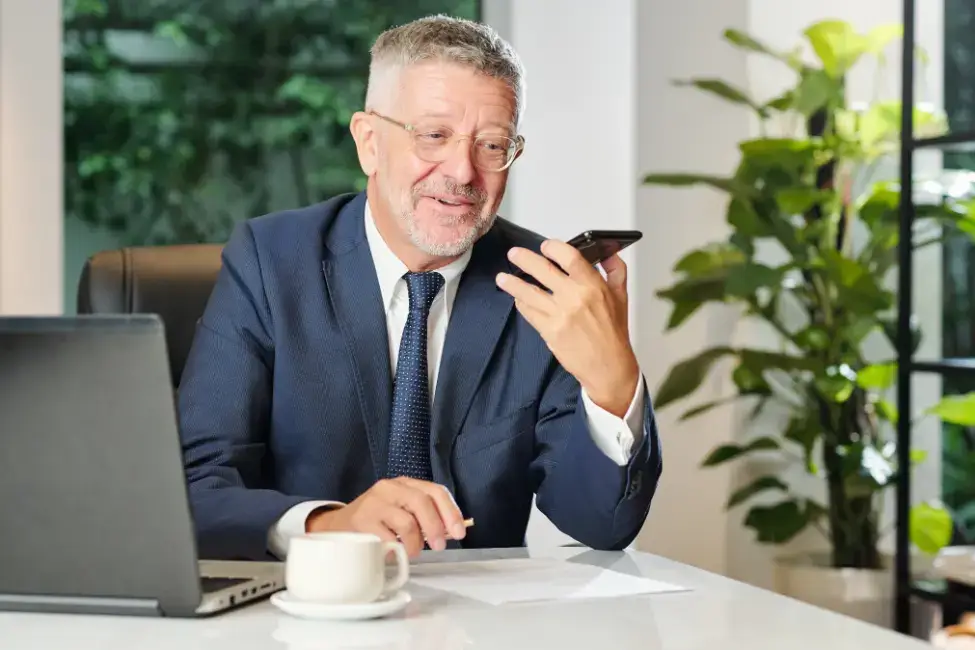 Symbolbild Vertriebsbücher: Ein junger Mann am Computer zwischen zahlreichen Unterlagen.